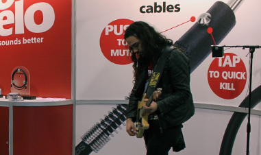 man playing electric guitar at trade show
